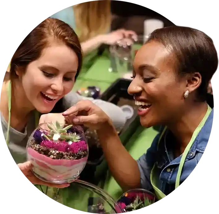 Two ladies laughing, making terrariums at girls’ night.